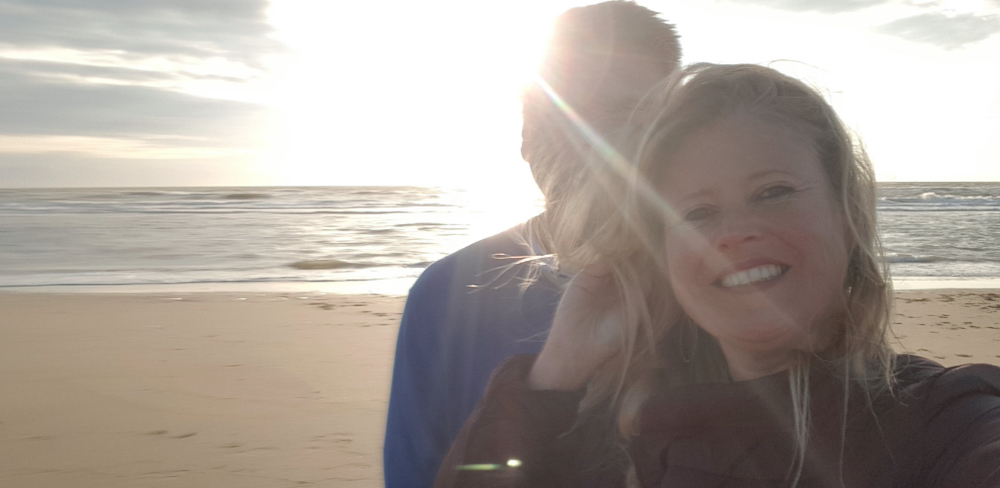 Roy en Katrín aan het strand met de zee en de ondergaande zon op de achtergrond.